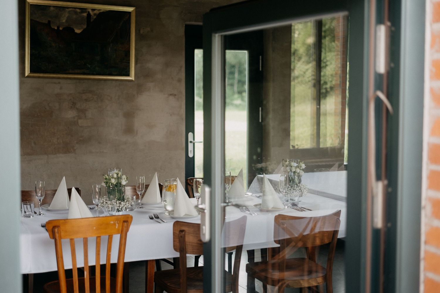 Restaurant interior with white tablecloths and wooden chairs visible through doorway.