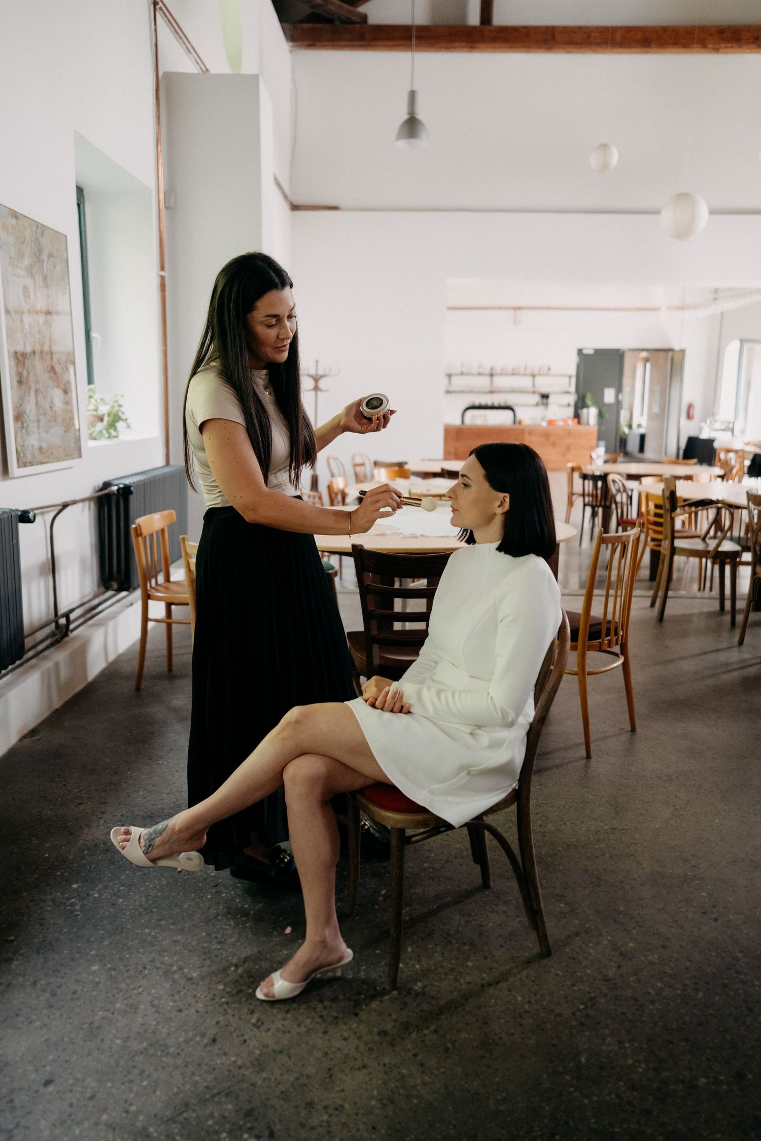 Minimalist indoor photoshoot featuring white dress against industrial space with wooden furniture.