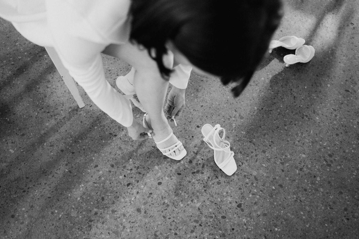 Black and white photo showing ballet shoes and feet on a concrete floor.