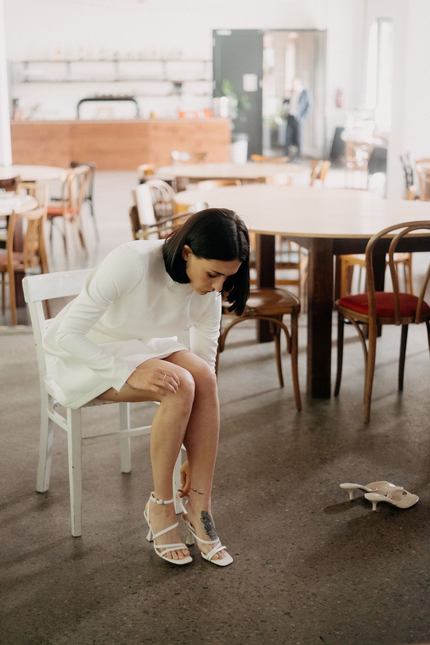 Artistic series showing details of white dress and shoes in minimalist indoor setting.