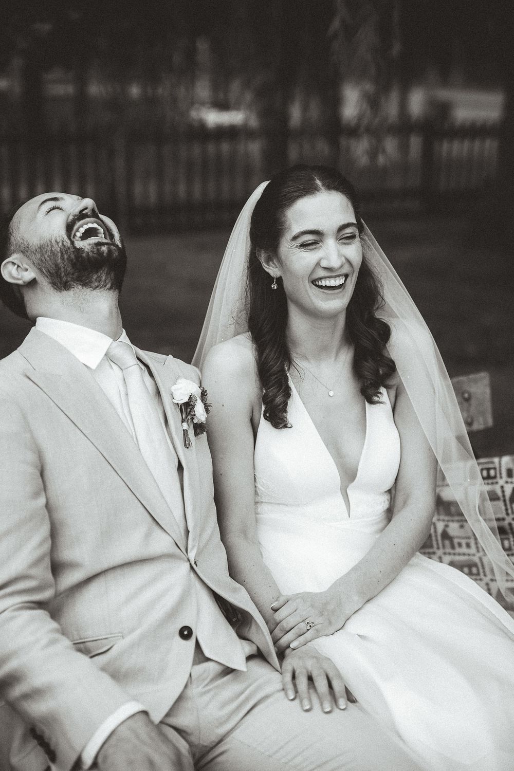 Black and white photo series of a couple in wedding attire sharing candid laughter together on a bench.