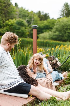 Couple laying in garden deck surrounded by yellow flowers and greenery on a sunny summer day.