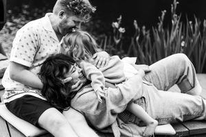 A playful black and white scene of a family sharing laughter and cuddles while relaxing outdoors.
