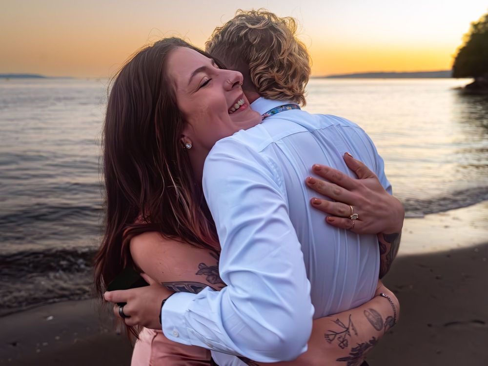 Couple sharing intimate moments during sunset photoshoot at a scenic beach location.