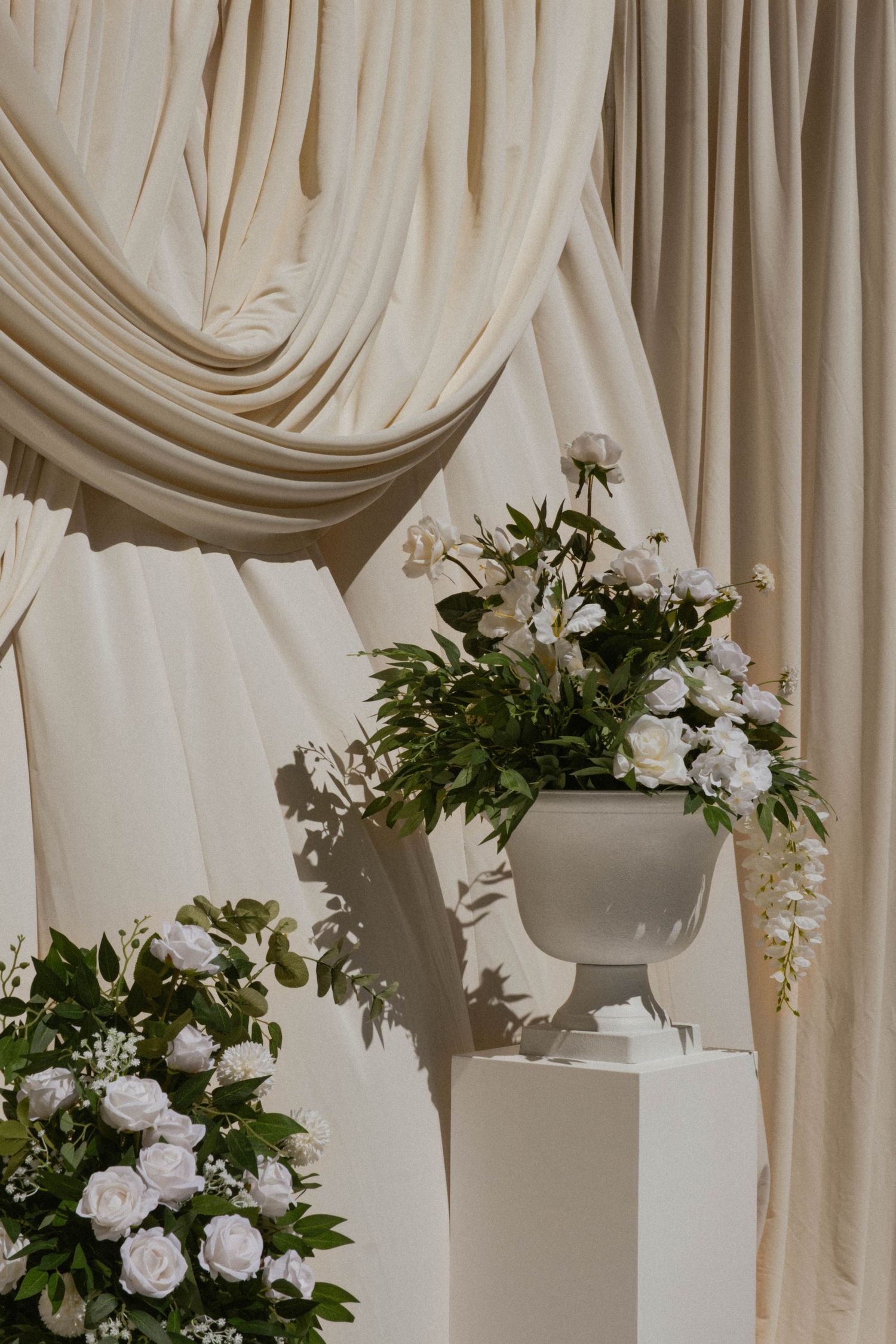 Elegant white draping and hanging floral arrangements create a romantic wedding backdrop.
