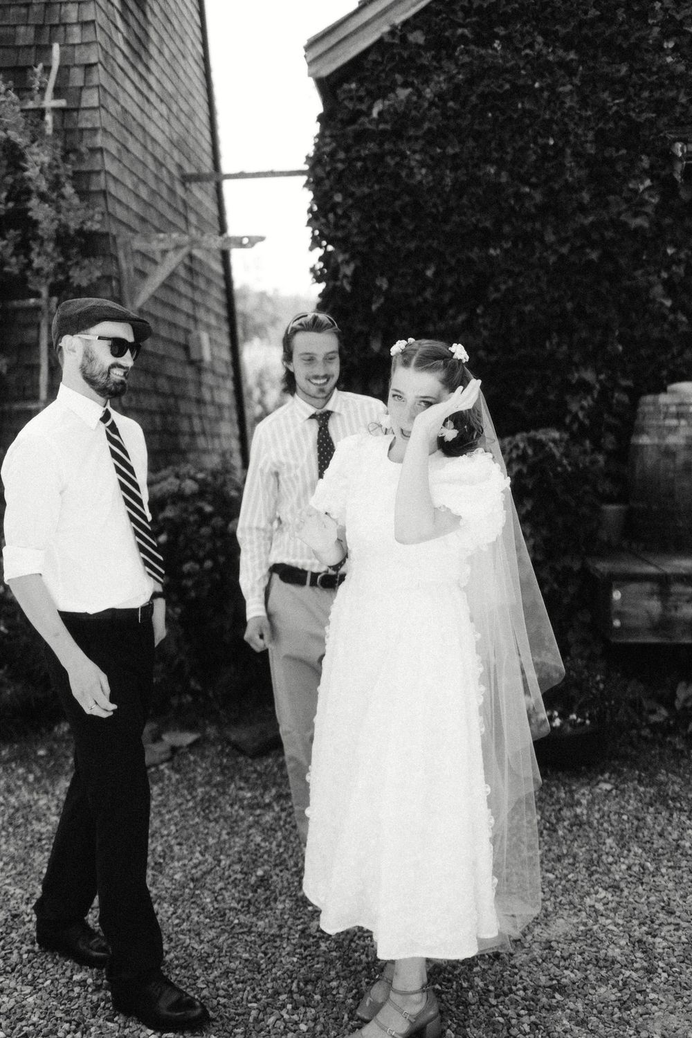 Black and white photos of playful moments outside a brick building with wedding attire.
