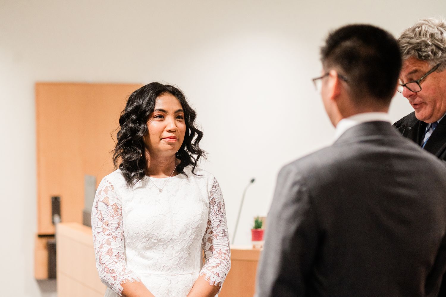 A bride and groom share a joyful moment during their wedding celebration in a warm-lit indoor setting.