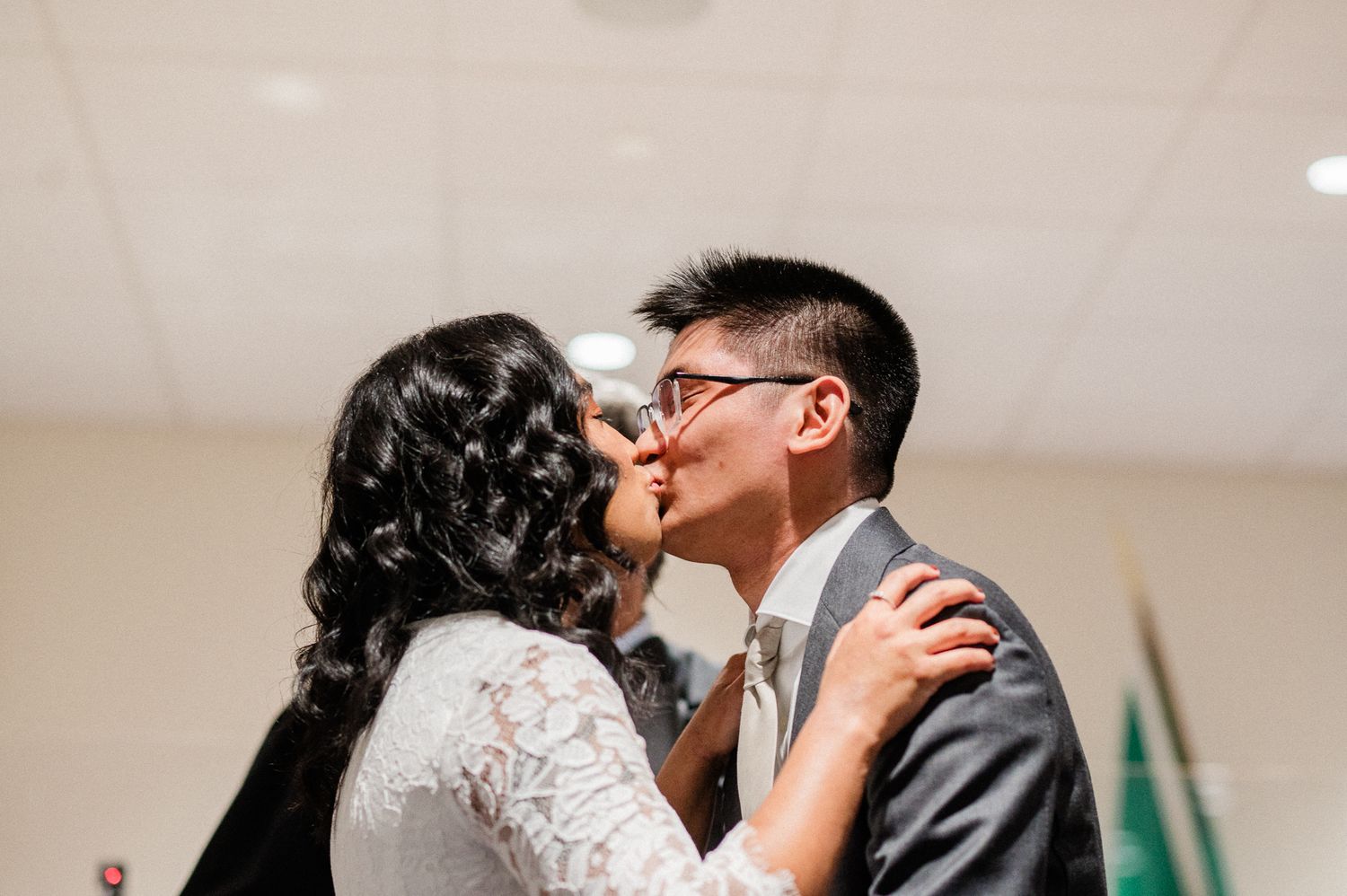 A couple in wedding attire share a romantic kiss during their courthouse wedding