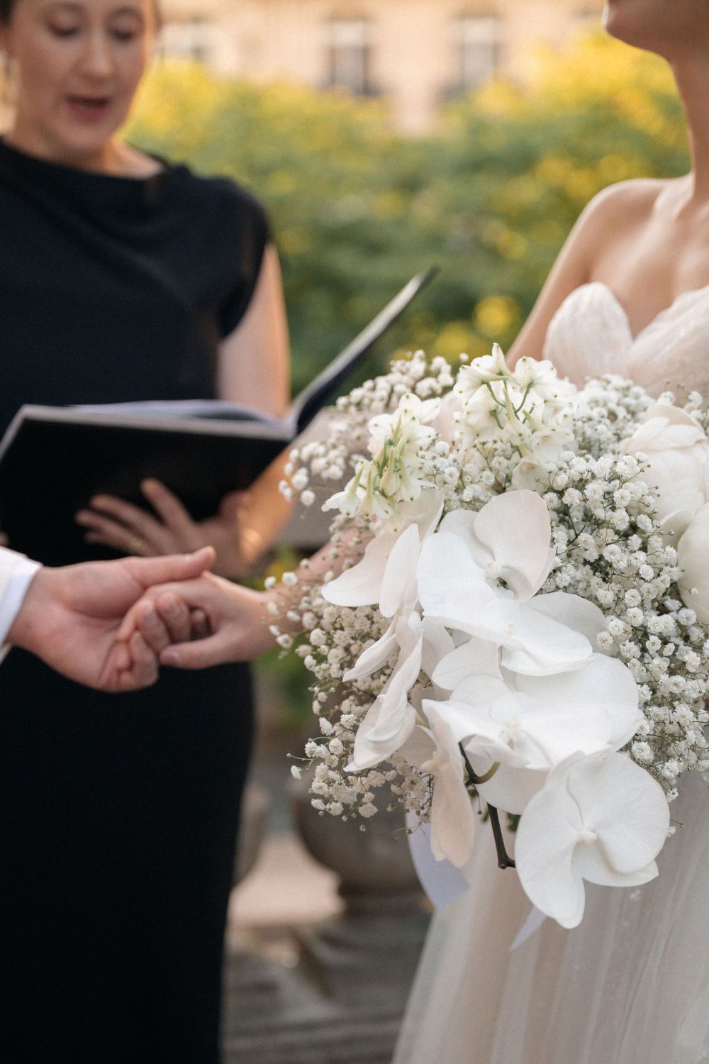 White bridal bouquet with baby's breath and delicate flowers during an outdoor wedding ceremony.