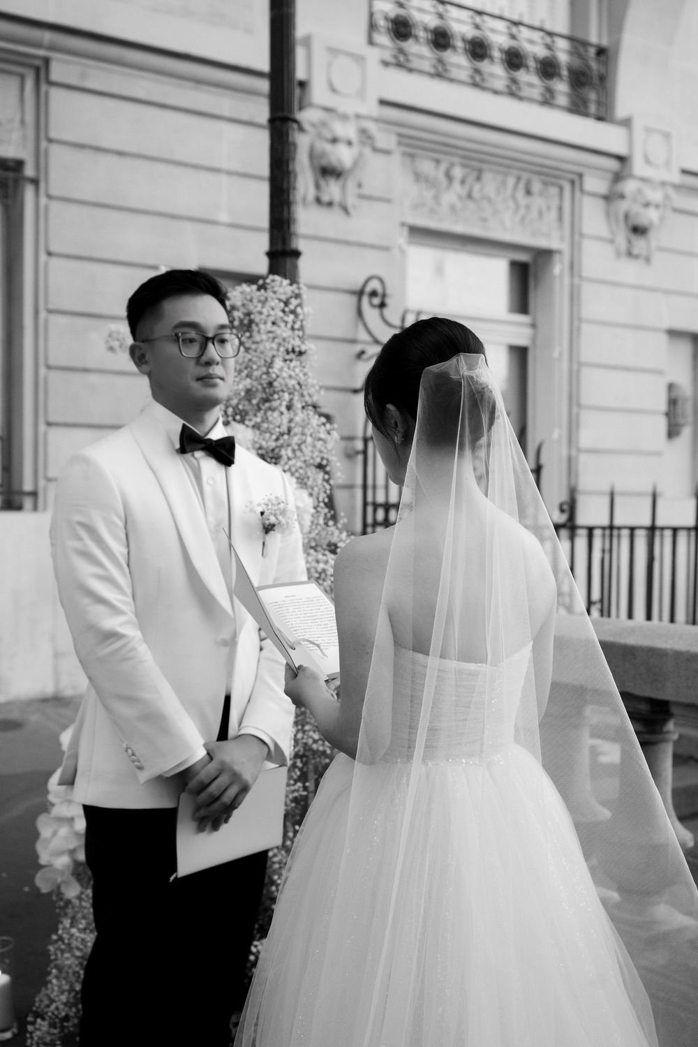 A black and white wedding photo series captures tender moments between newlyweds on a classic Parisian terrace.