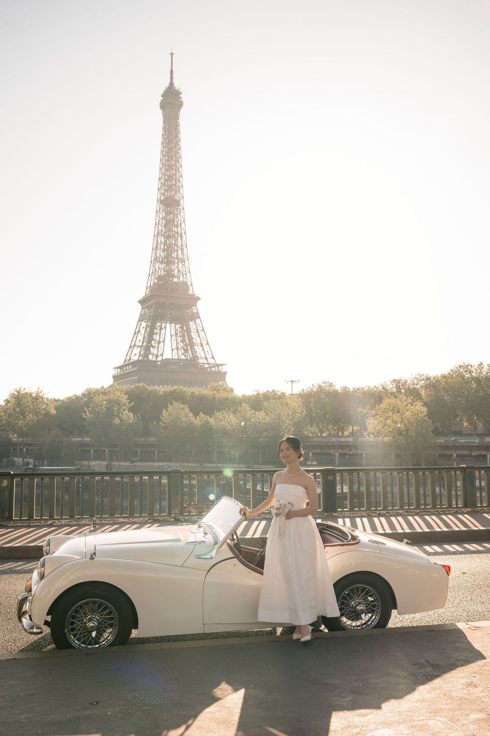 Dreamy Paris wedding photoshoot featuring a white vintage automobile with the Eiffel Tower in golden light.
