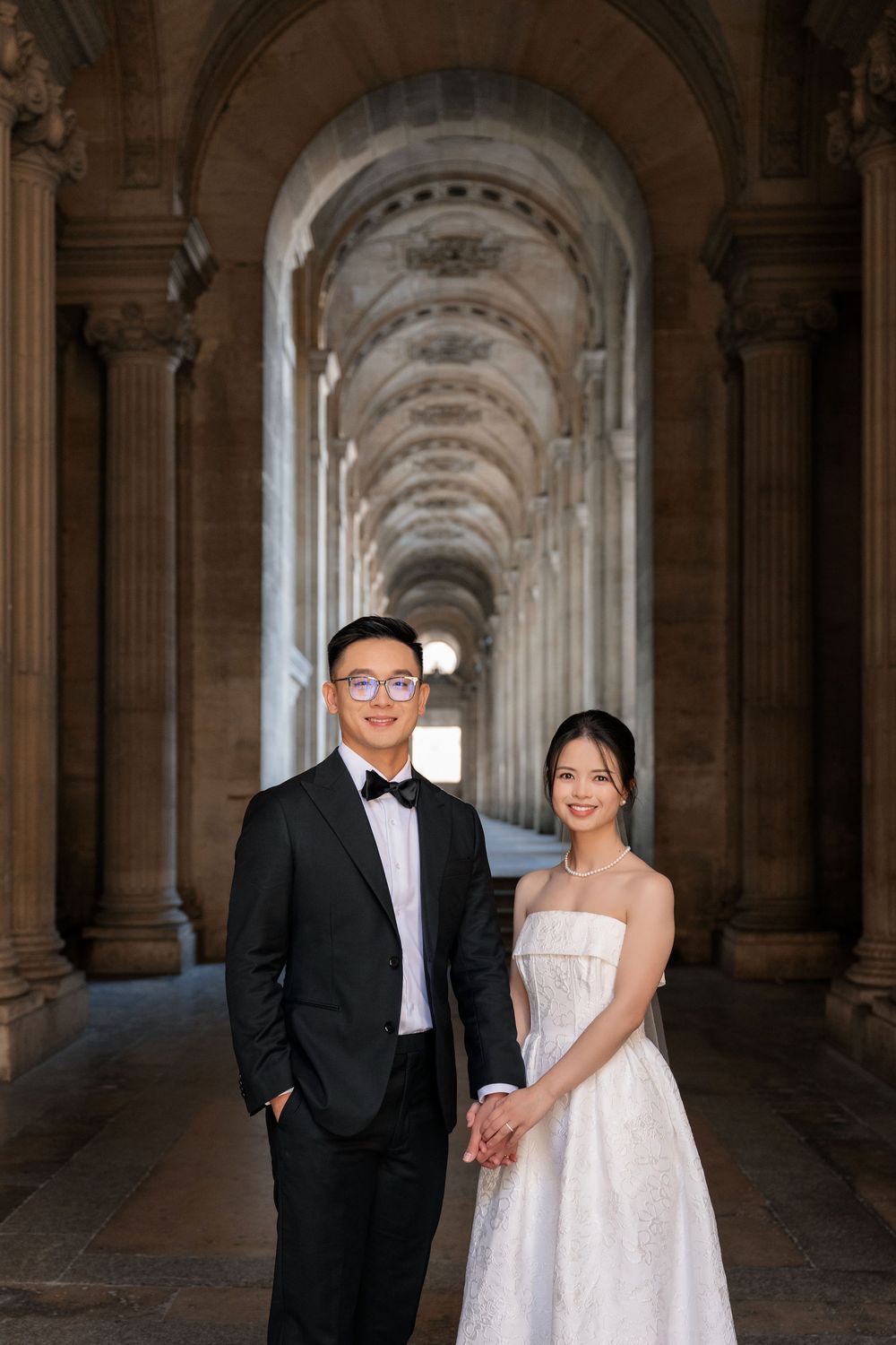 Wedding photo in an elegant stone colonnade with dramatic lighting.