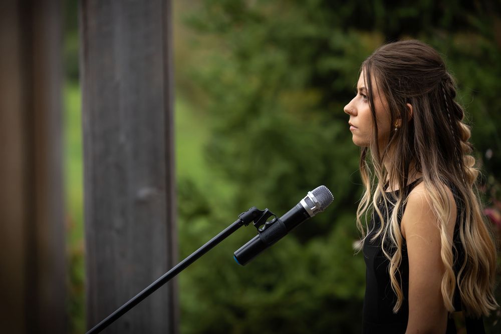 Wedding ceremony speakers and microphone setup outdoors with autumn foliage in background.