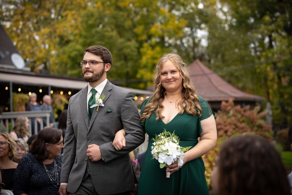 Wedding guests gathered under string lights at an outdoor autumn reception.