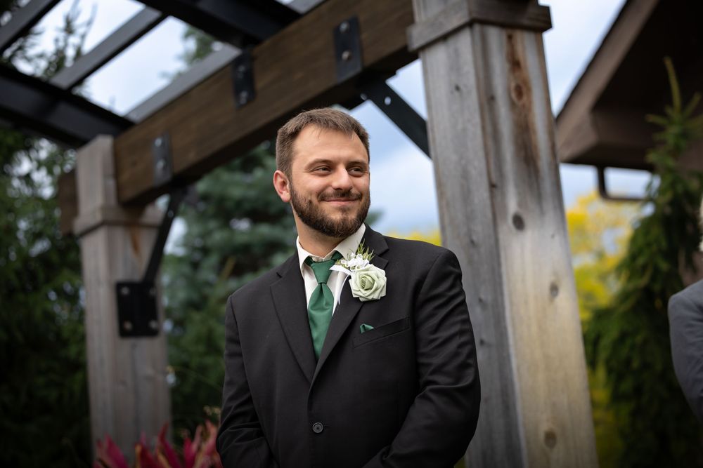 Wedding party members standing beneath a rustic wooden pergola.
