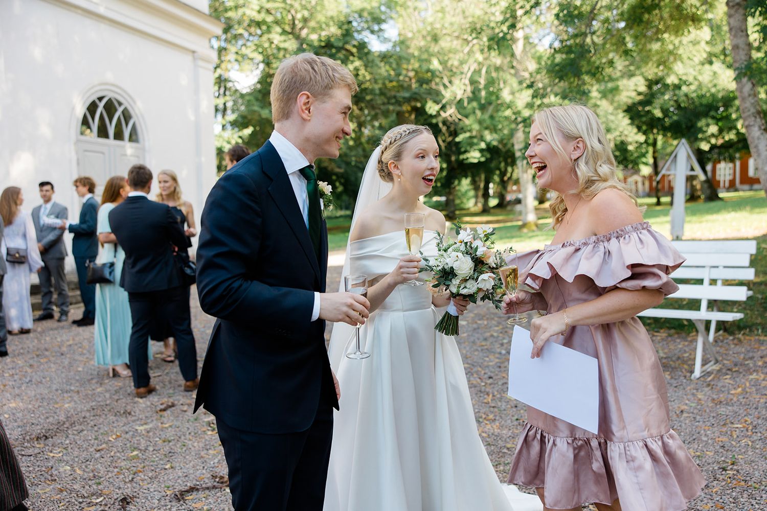 Wedding party celebrates together outdoors in a garden setting during a joyful summer celebration.
