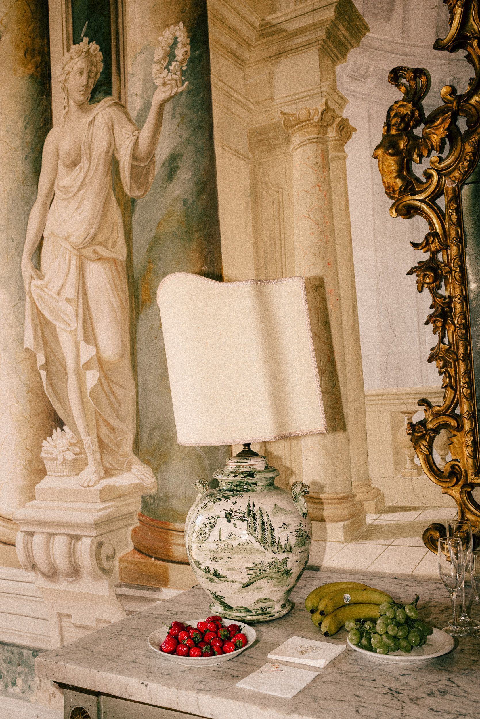 Elegant white statues and decor adorn a classical interior with a plate of fresh red strawberries on display.