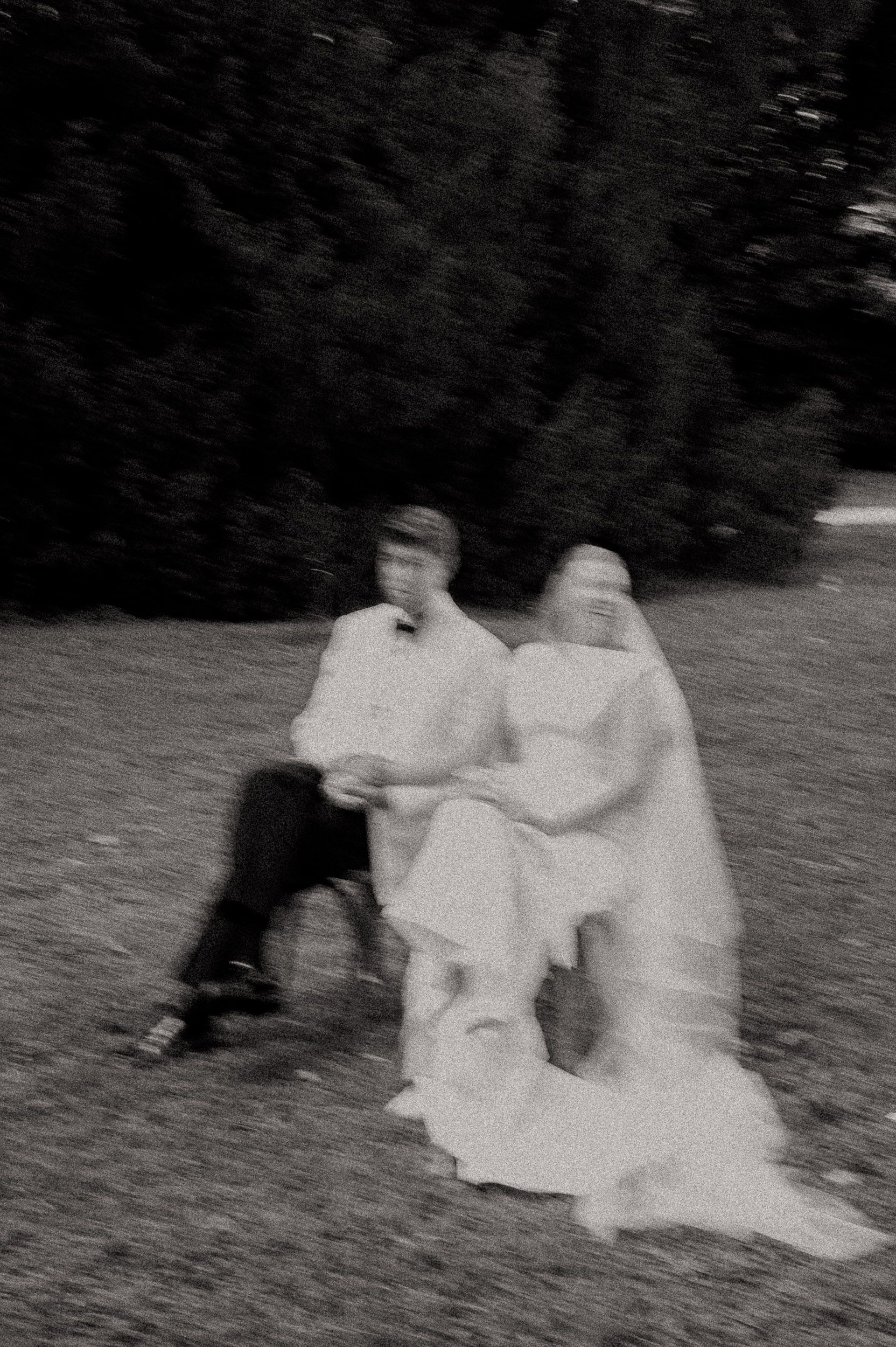 Blurry black and white sequence showing two figures rolling down a grassy hill together.