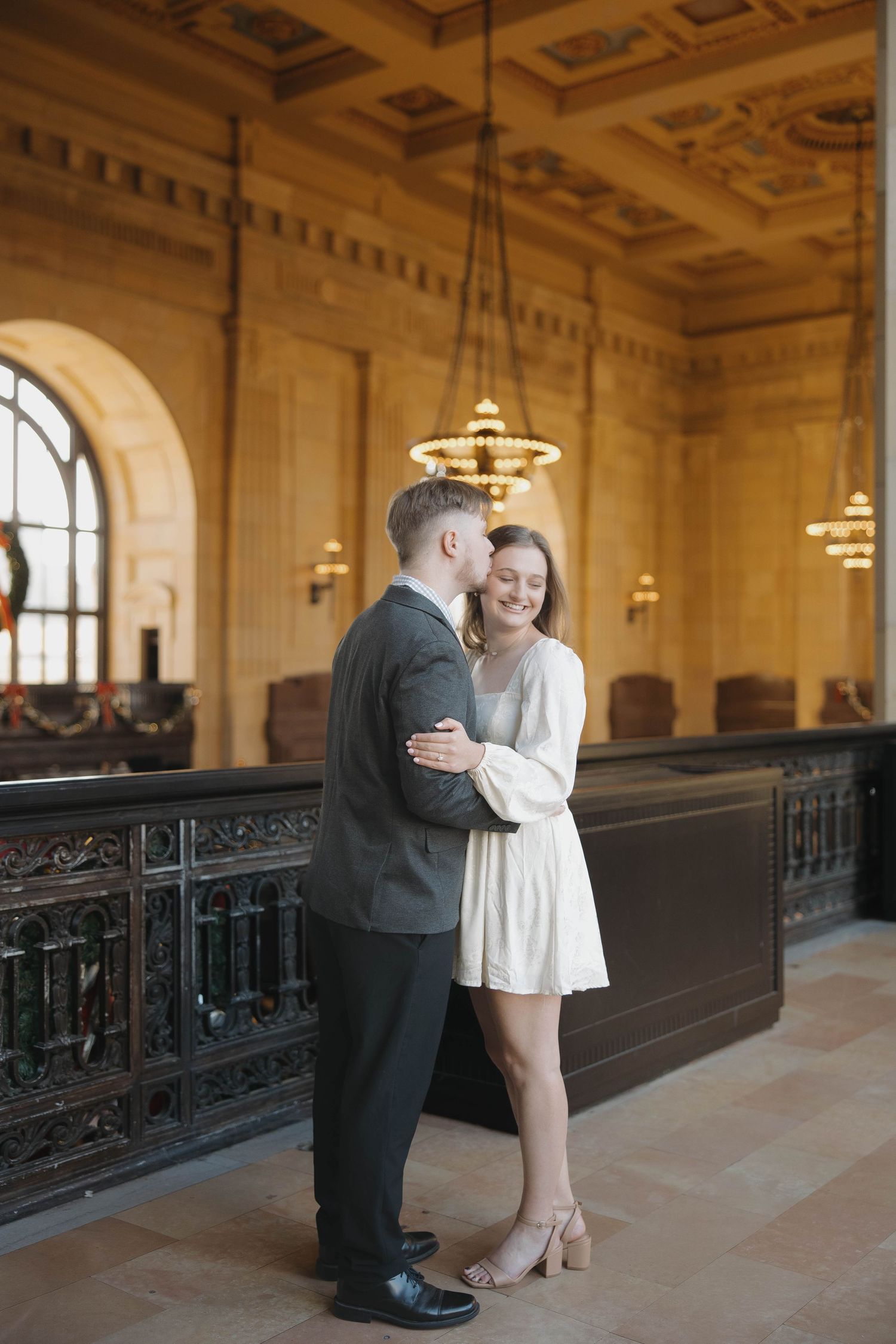 A romantic moment captured in an elegant hallway with ornate ceiling details and vintage lighting fixtures.
