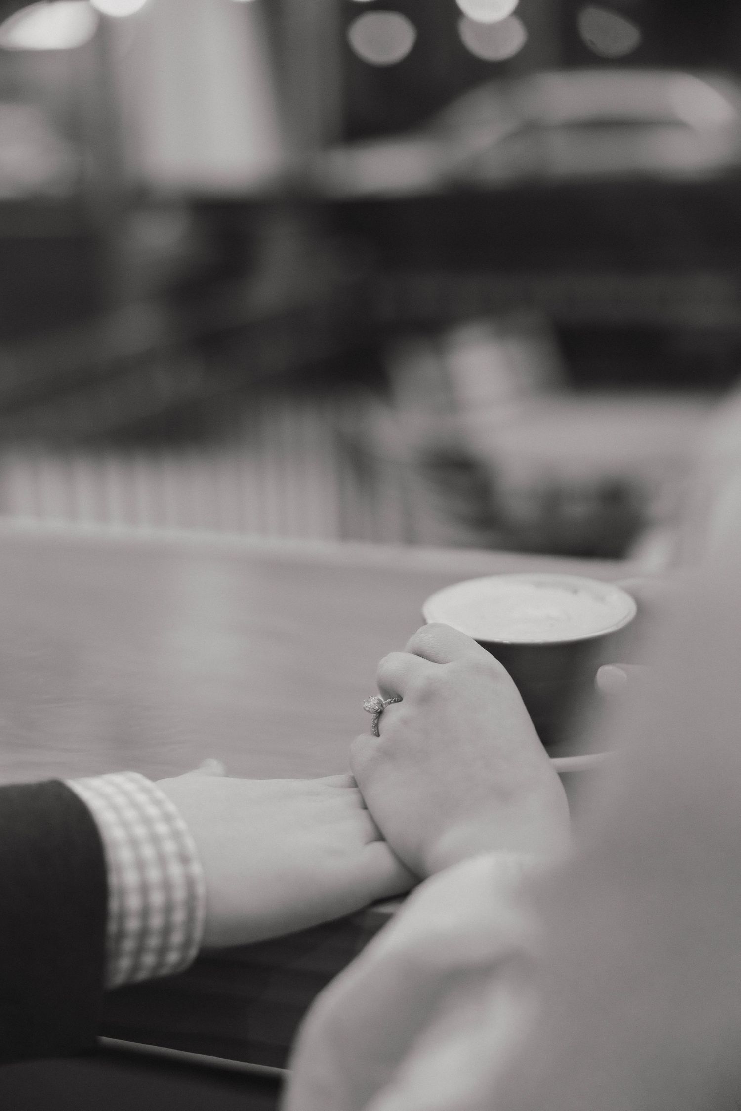 Close-up shot of hands gently touching across a table in a romantic moment.
