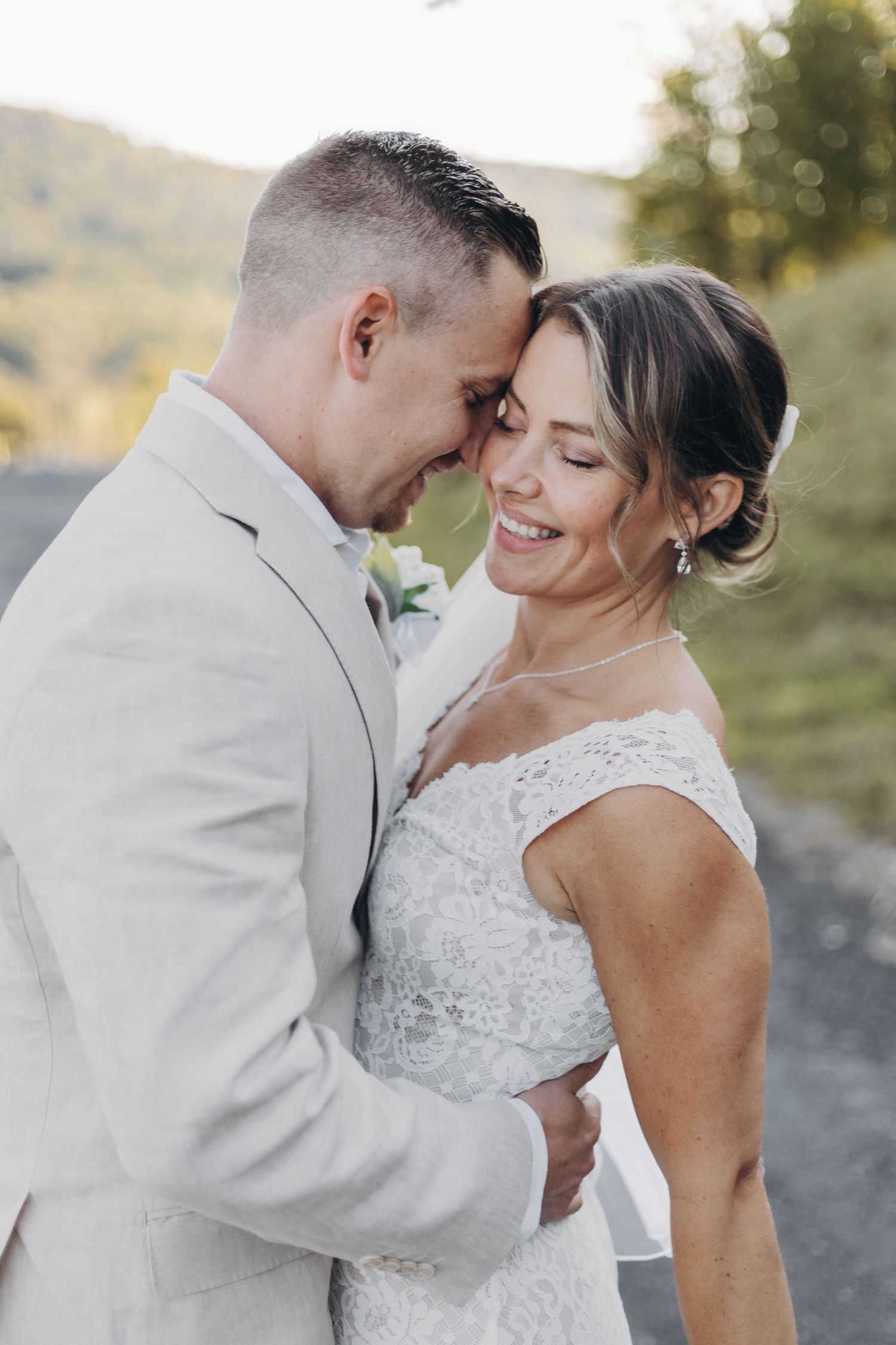 A romantic wedding couple shares intimate moments in white attire against a soft outdoor backdrop.