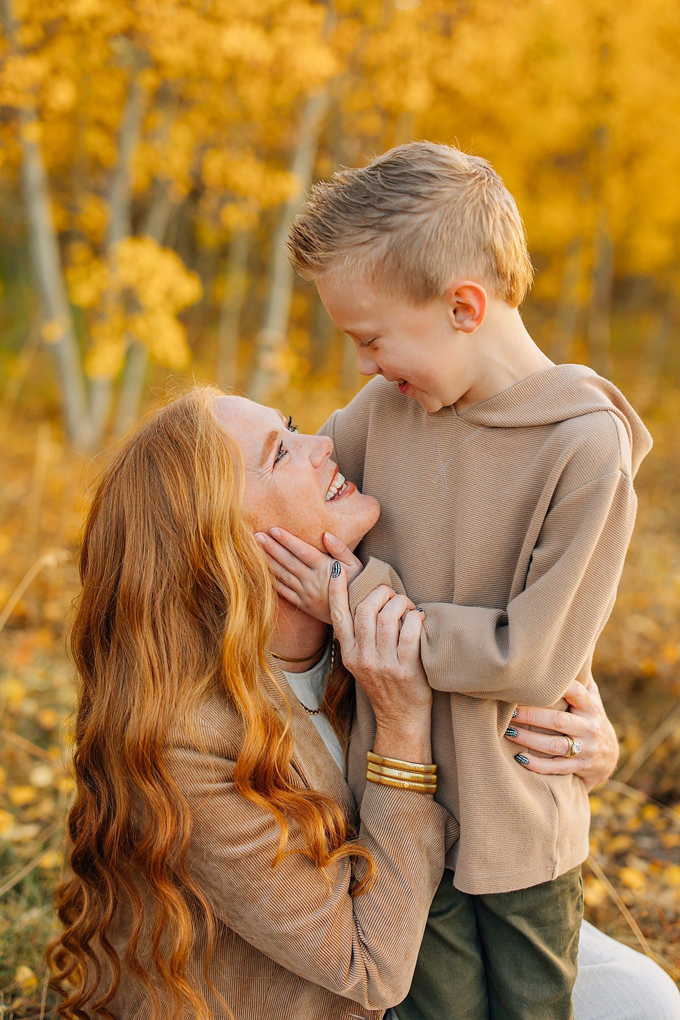 An intimate moment captured between two people wearing neutral tones against vibrant yellow fall foliage.