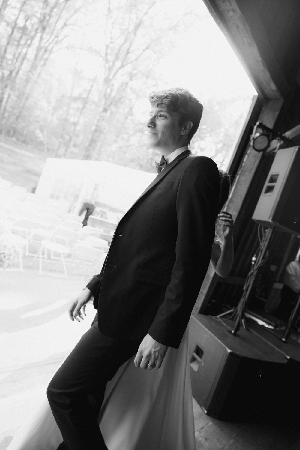 Black and white photo of a person in a suit gazing out a window in contemplative pose.