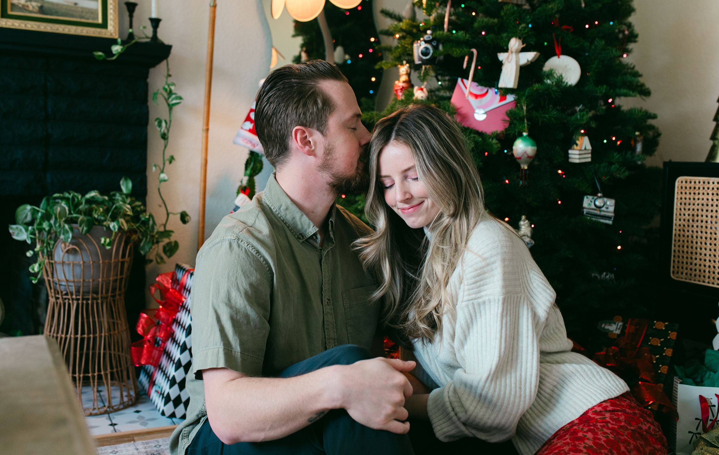 A romantic couple shares intimate moments in front of a decorated Christmas tree during the holiday season.