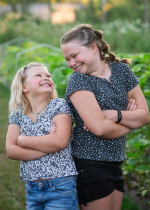 A candid sequence of joyful hugs and laughter shared between two people in a lush green outdoor setting.