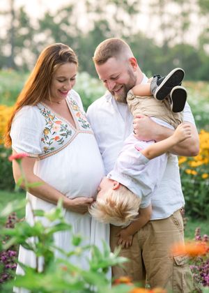 A couple shares tender moments in a blooming flower garden during a summer photo session.