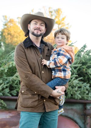 A parent and child share a heartwarming moment while picking out a Christmas tree at a festive tree lot.