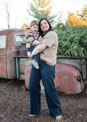A rustic outdoor scene with overalls and a sweater against a vintage truck and evergreen trees in autumn.