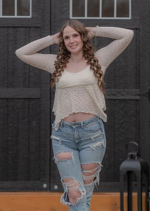 Stylish outfit featuring distressed denim and cream sweater against dark wall.
