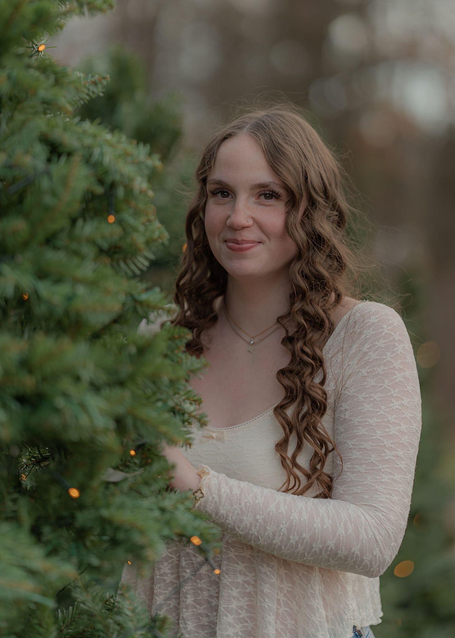 Outdoor winter portrait among evergreen trees with twinkle lights.
