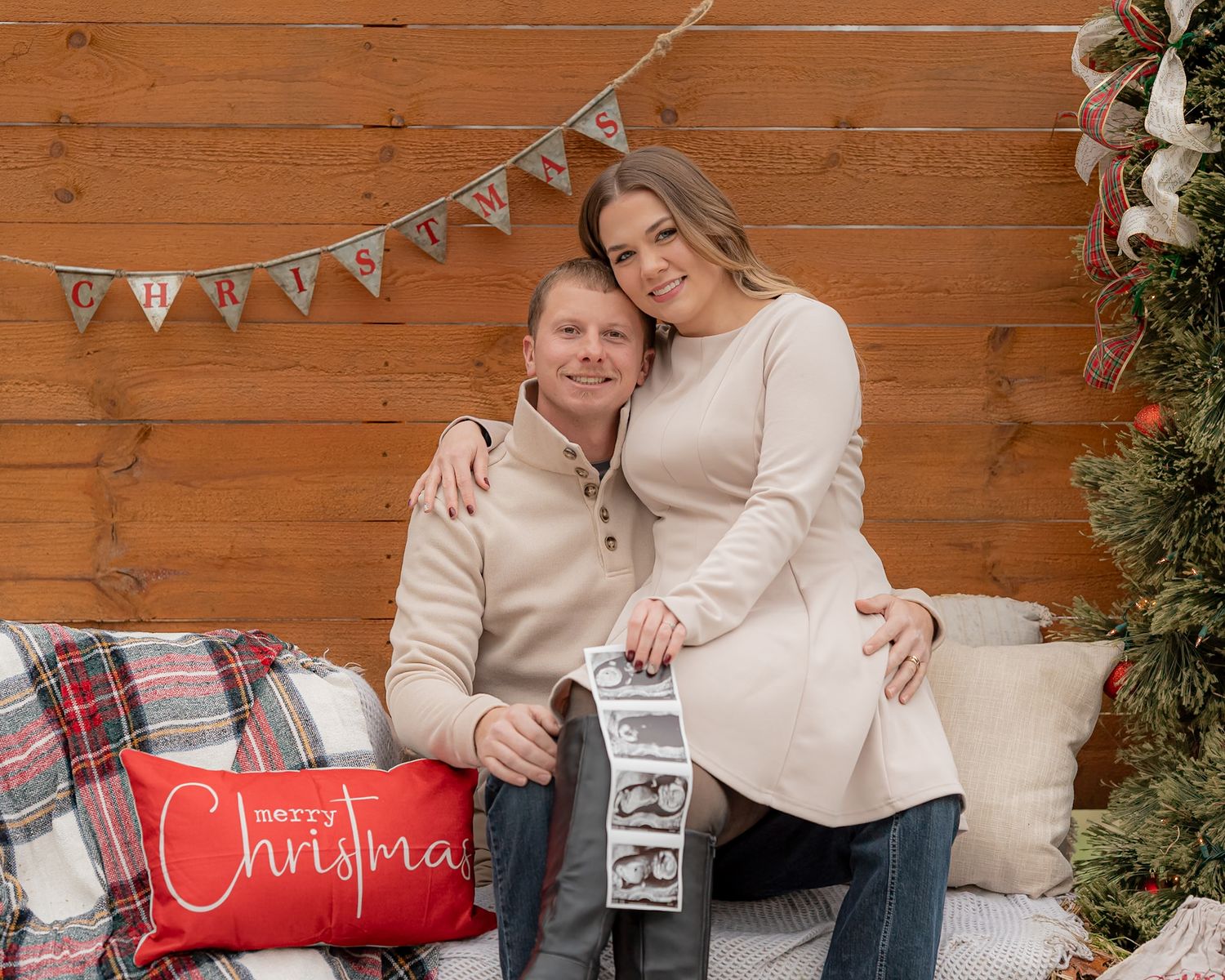 A holiday photo session with Christmas decor and white bunting against wooden walls.