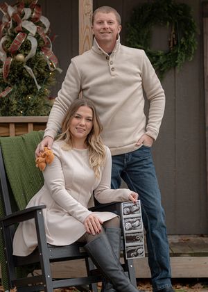 A couple sits on outdoor furniture during a winter photo session.