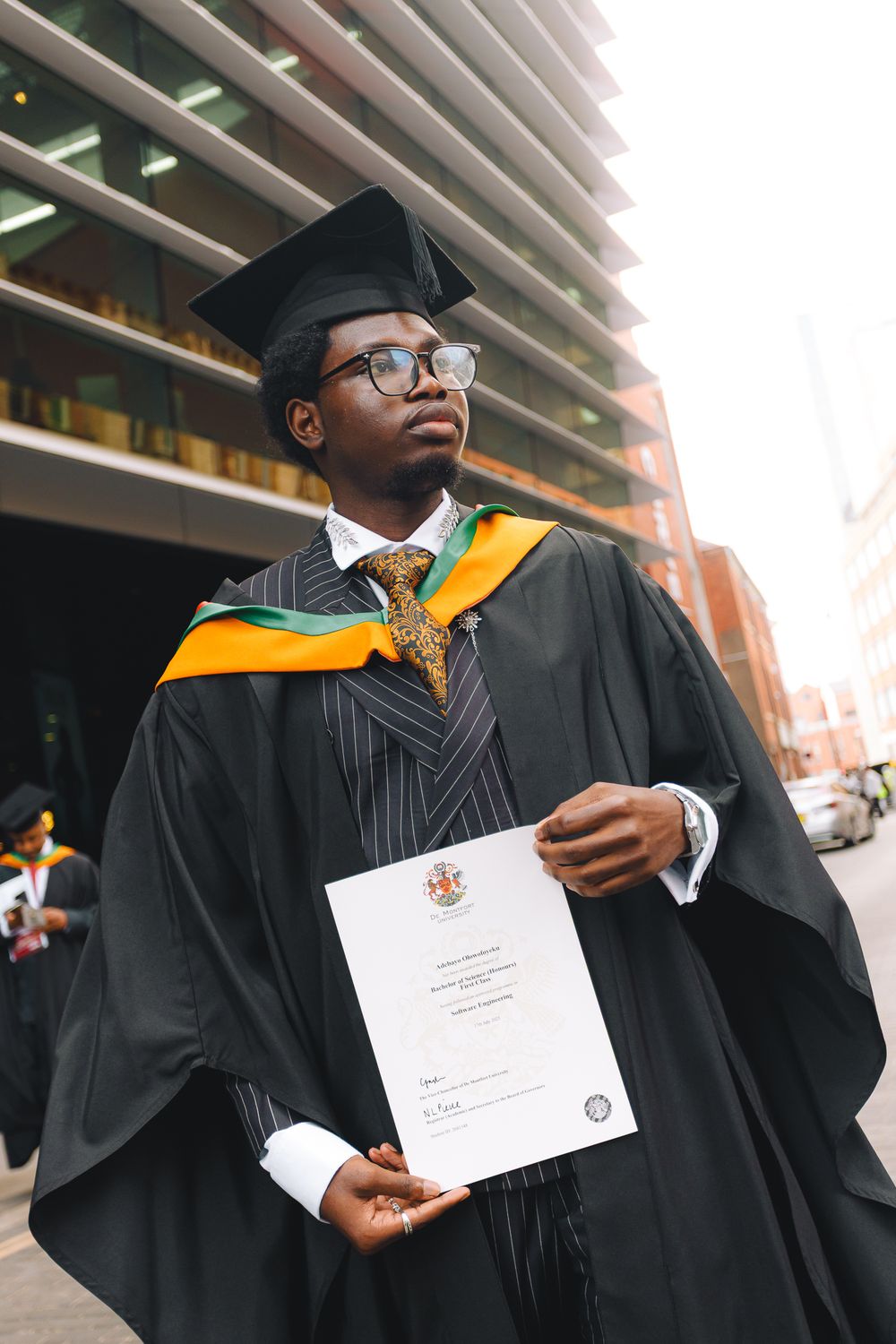 Graduate in black academic regalia holds diploma during commencement ceremony at university.