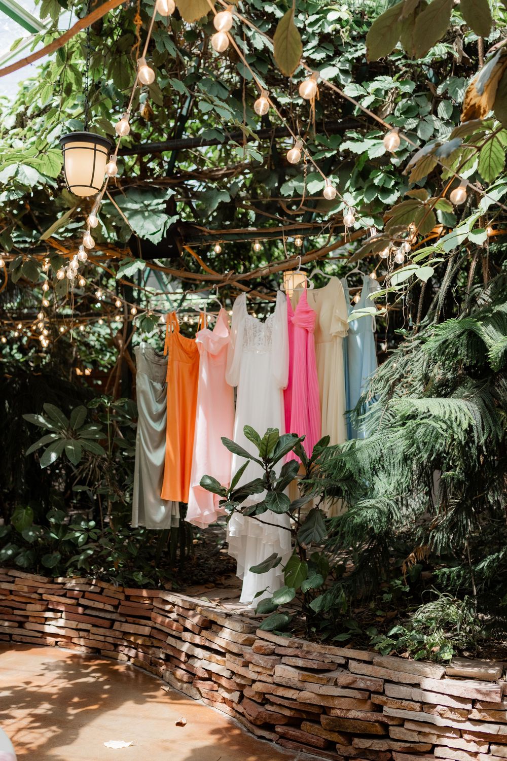 Bridesmaid dresses hanging beneath string lights before a Utah wedding