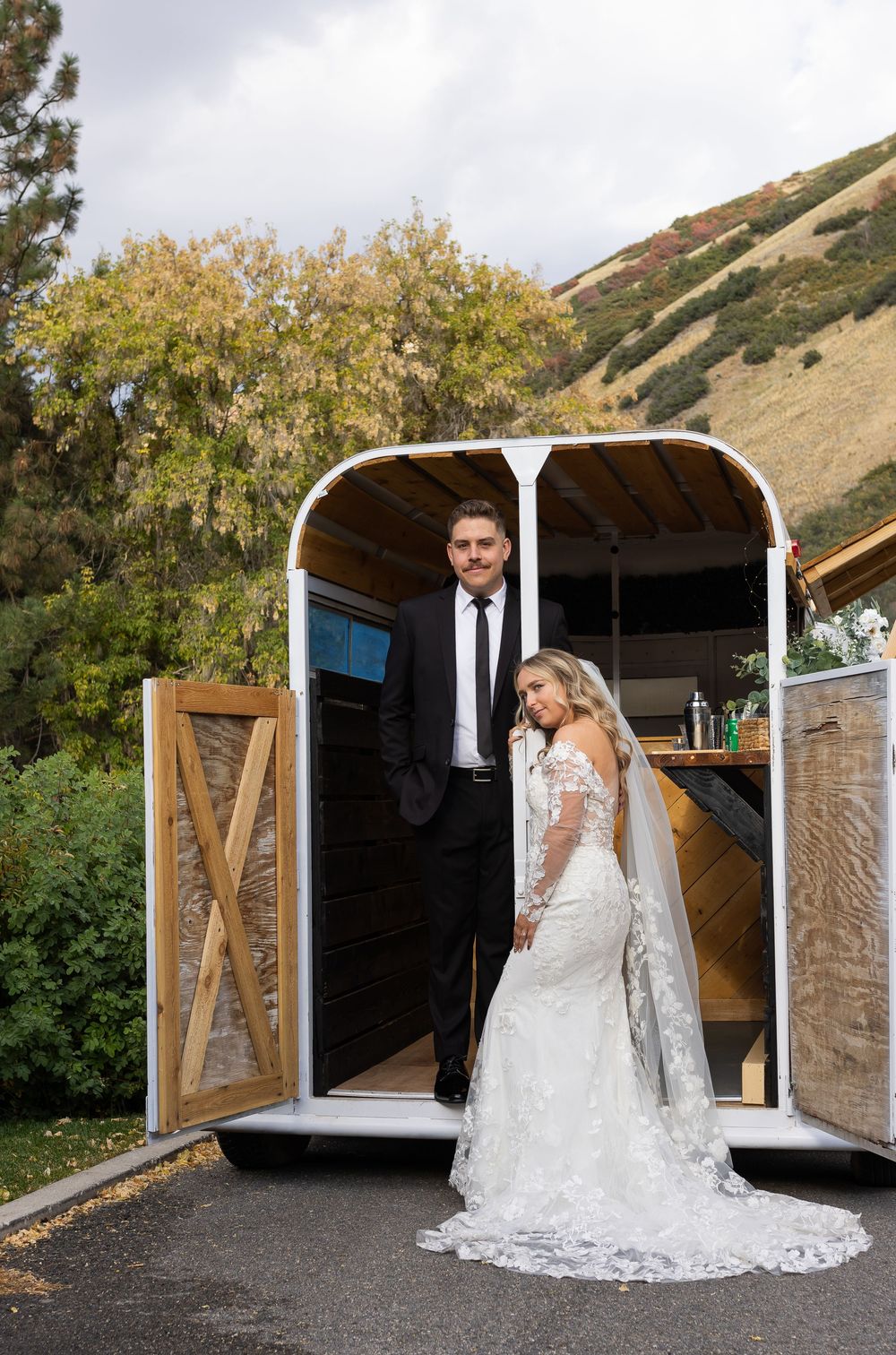 Bride and groom standing together outside a rustic trailer venue during a Utah wedding photography session