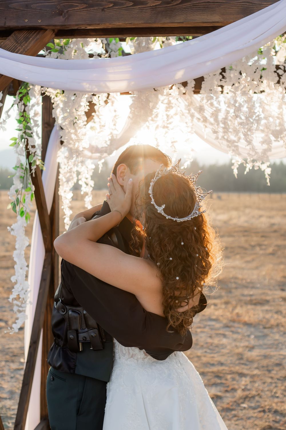 Bride and groom kissing beneath a wooden arch during a Montana wedding ceremony
