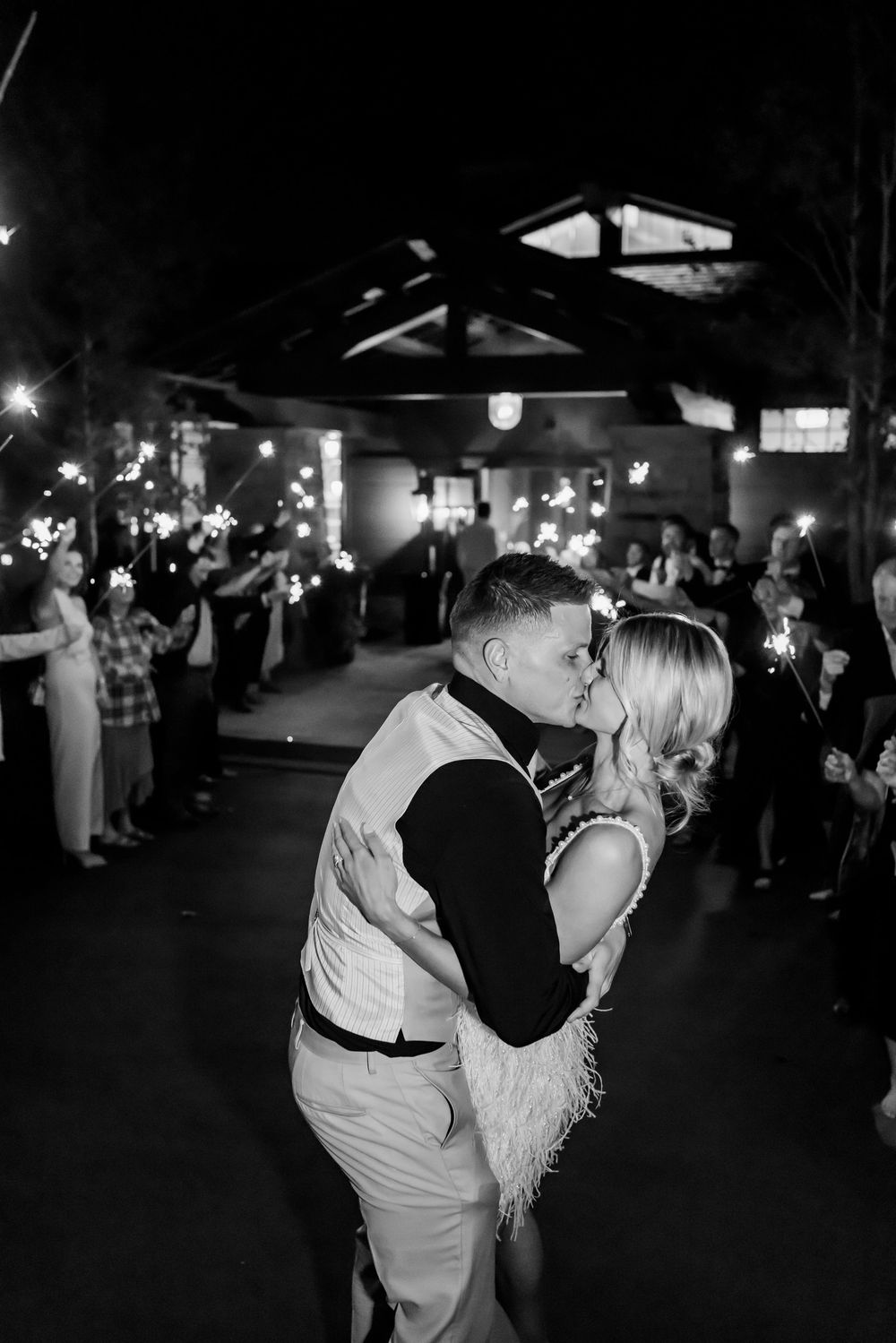 Bride and groom kissing during sparkler exit at a Utah wedding captured in black and white