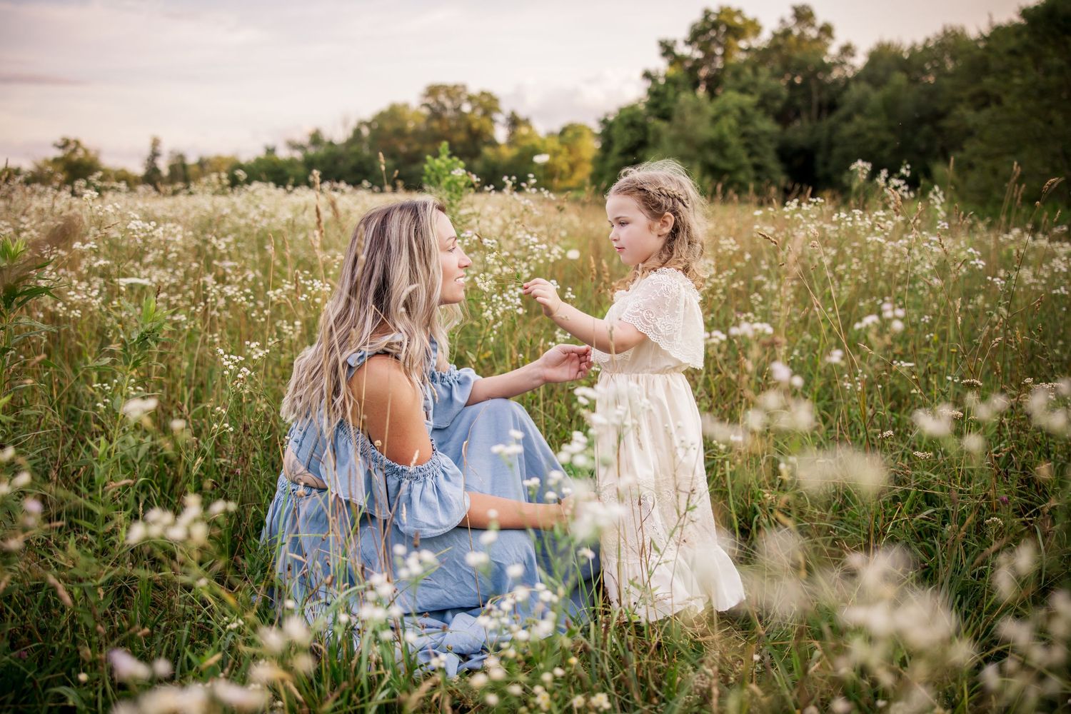 Two people share a tender moment in a summer wildflower meadow during golden hour.