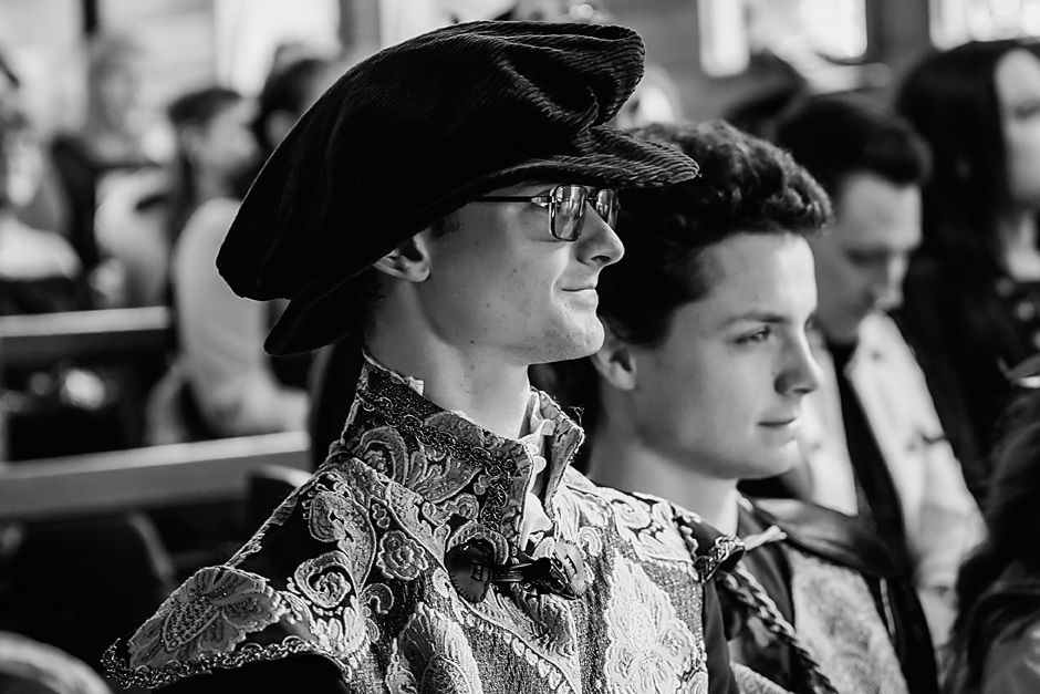 Black and white photo of spectators in sunglasses watching a sporting event from stadium seats.