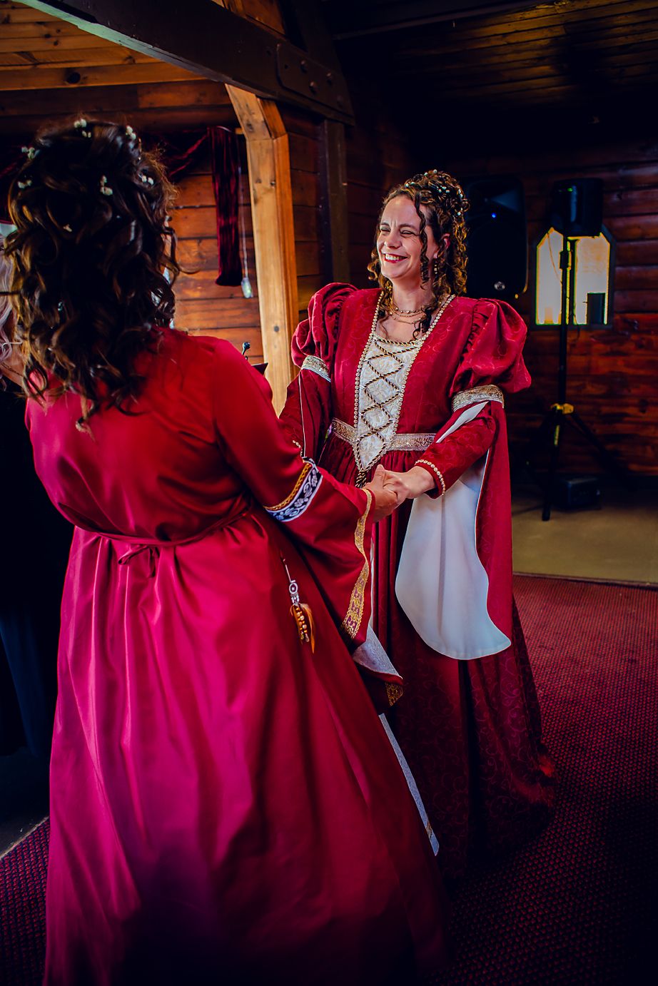 Two people dance together in a rustic log cabin venue wearing red and white formal attire.