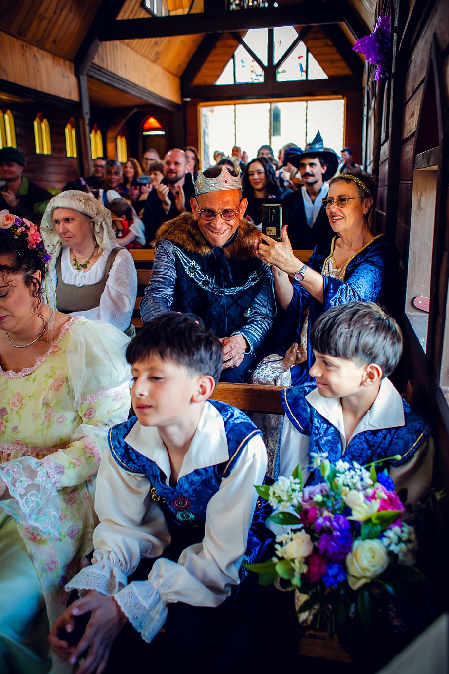 Wedding guests laugh and smile together during a joyous celebration in an indoor venue with floral decorations.