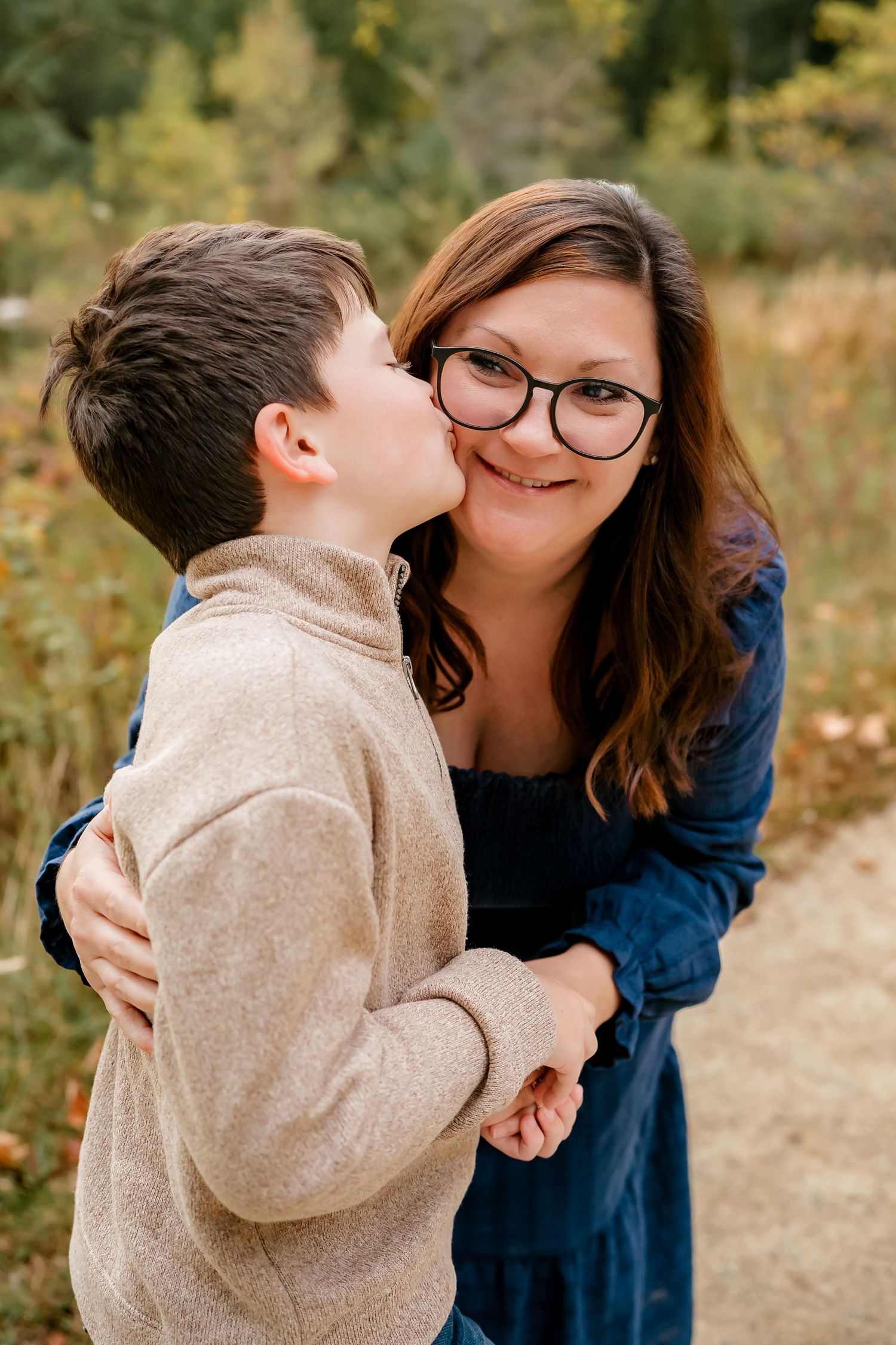 A tender moment between parent and child in casual clothing embracing outdoors during autumn.