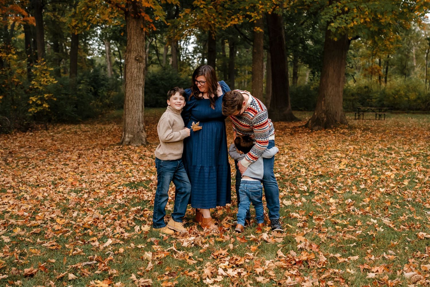 A series of fall family photos captured in a park with orange autumn leaves scattered on the ground.