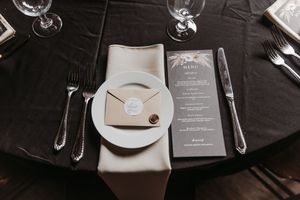 Elegant table settings with black tablecloths, wine glasses and place cards at a formal event.