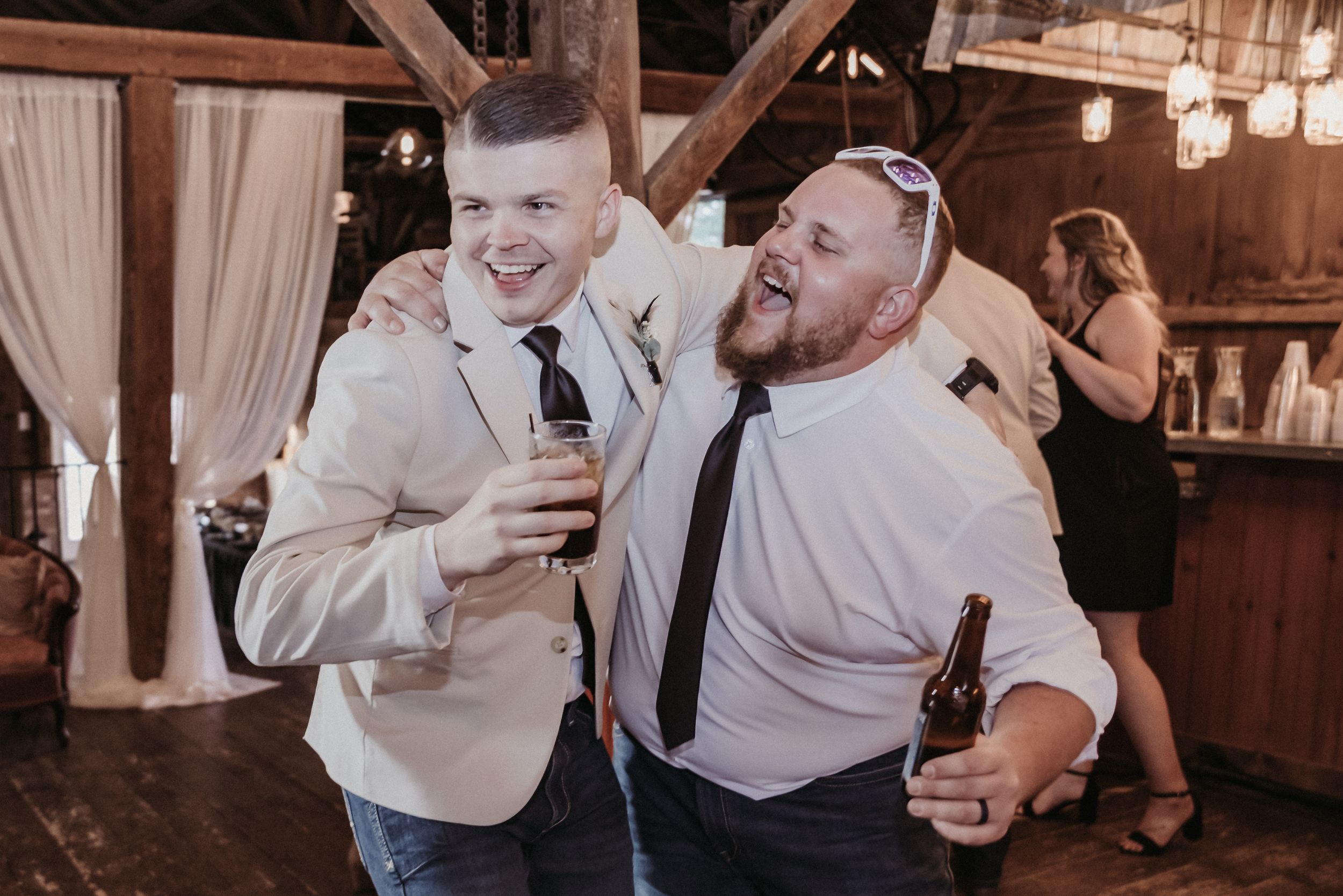 Wedding reception guests dancing and celebrating in a rustic barn venue with string lights.