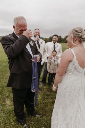 Wedding party members share a celebratory toast together in an outdoor field setting.